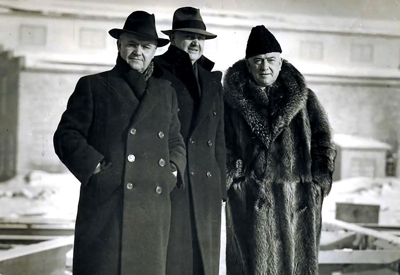 Photo des trois frères Simard vêtus avec des manteaux d'hiver et portant des chapeaux.
