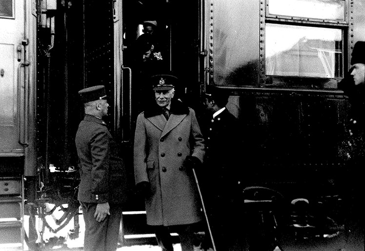 Trois hommes accueillent un homme et deux femmes sortant d'un train.