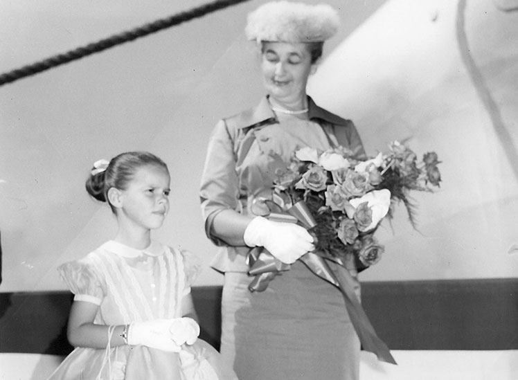 Une femme tenant un bouquet de roses en compagnie d'une fillette.