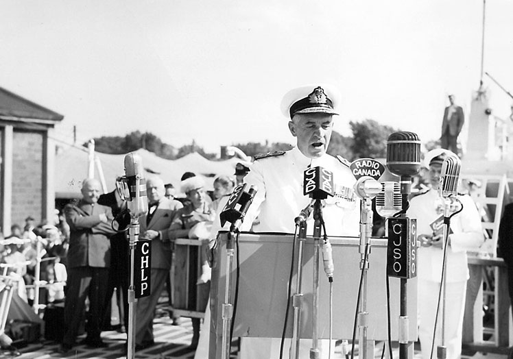 Un homme en uniforme blanc s'adressant à la foule.