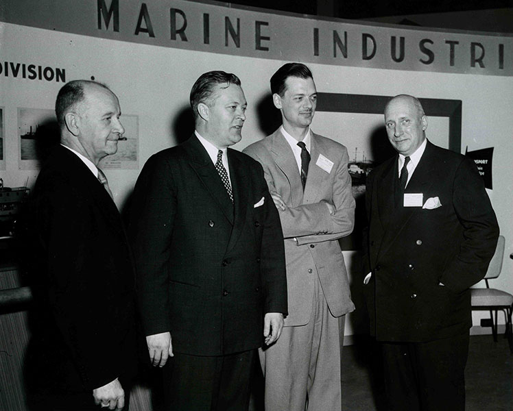 Quatre hommes devant le présentoir de Marine Industries