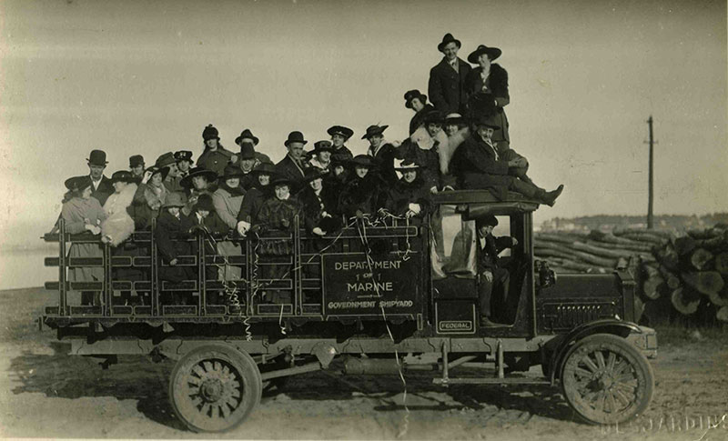 Plusieurs femmes et hommes juchés sur un camion appartenant aux Chantiers du Gouvernement.